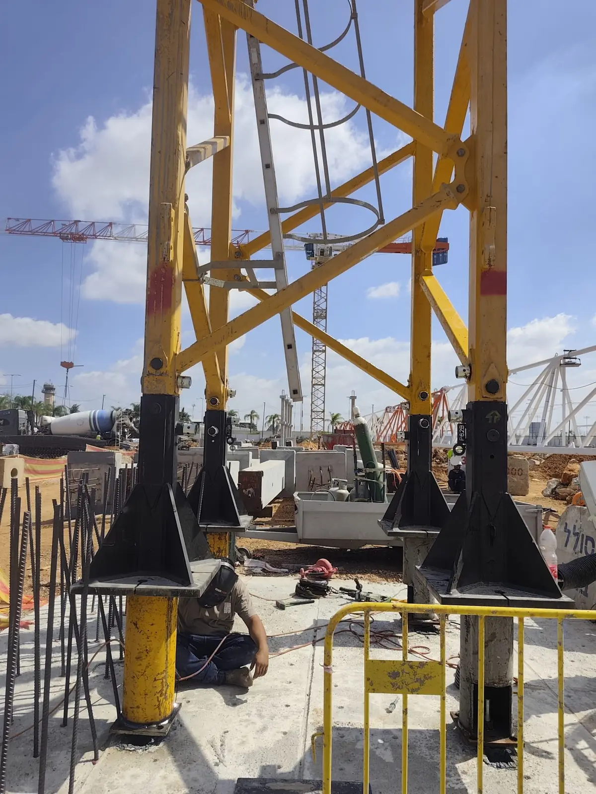 ארבע רגלי השתילה של עגורן הצריח ניצבות על יסוד הבטון היצוק, ועובד מרתך באזור הבסיס