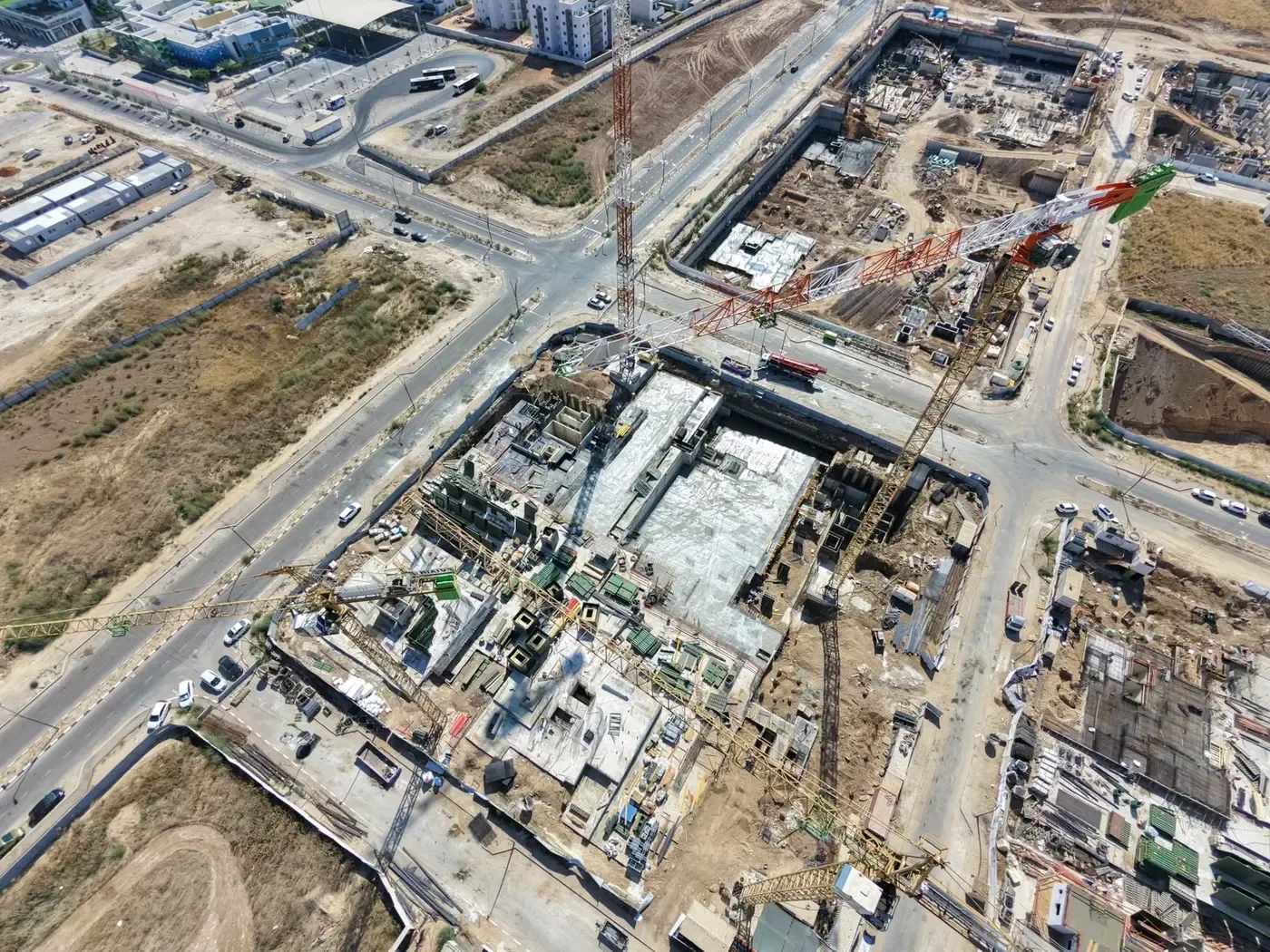 זרועות עגורני צריח חוצות מעל האתר, ומסביב מגרשי בנייה נוספים של שכונת כרמי גת
