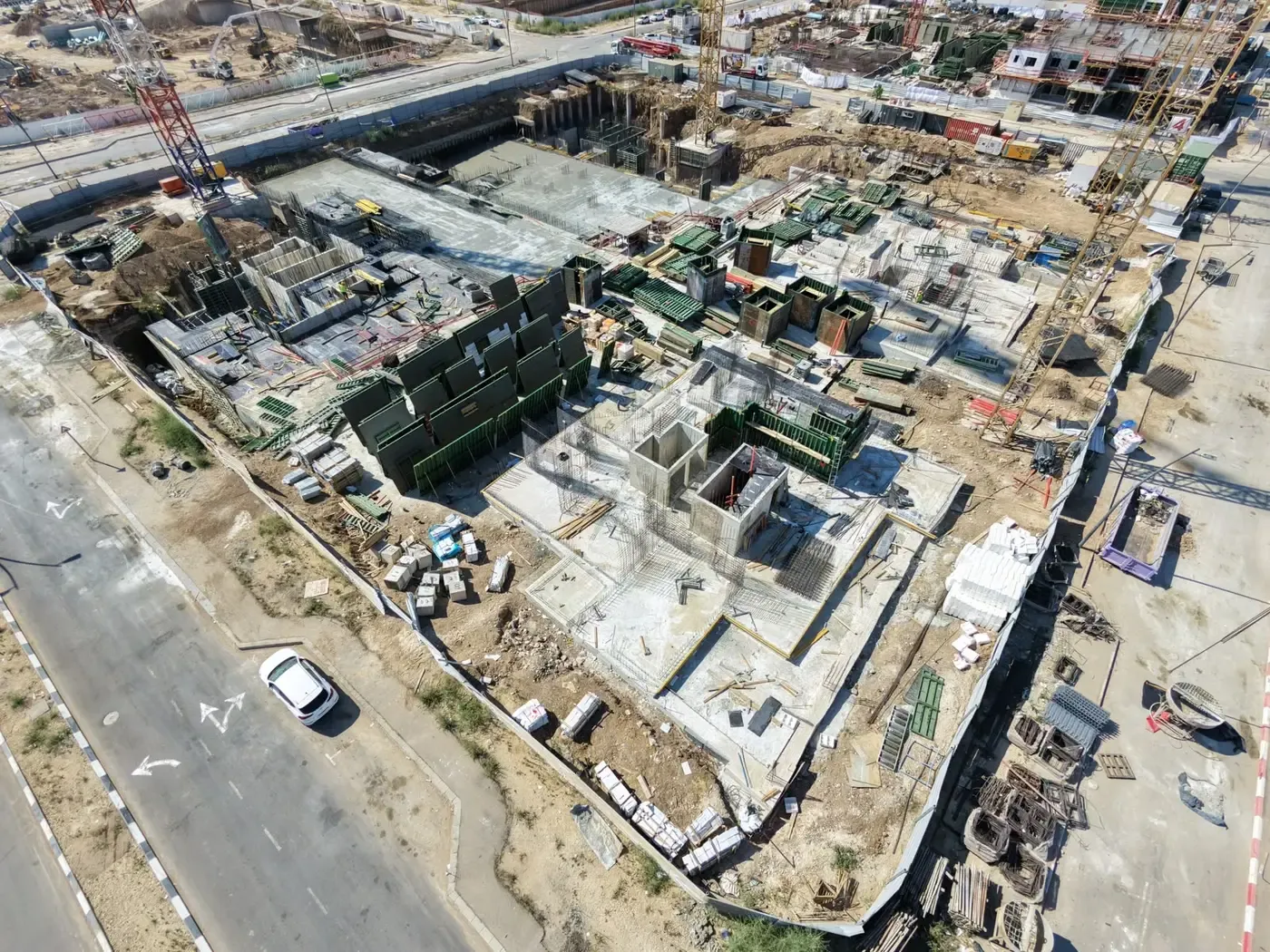 מבט מלמעלה על עבודות המרתף: טפסות קירות, ברזל זיון על תקרת הבטון וצוותי עבודה בין הגרעינים