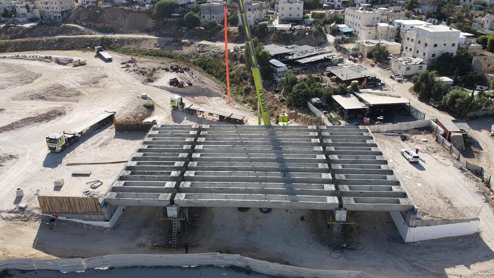 סיפון הגשר אחרי הנחת כל הקורות, לפני יציקת הלוח, עם משאיות ומנוף בשטח
