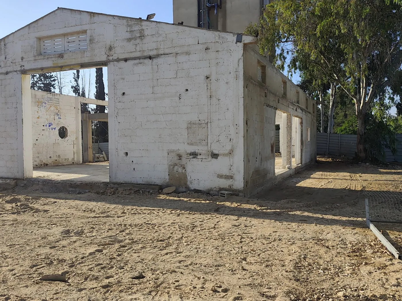 חזית הגמלון של מבנה האסם: קירות בלוקים קיימים עם פתחים, ומסביב חול ועקבות כלים